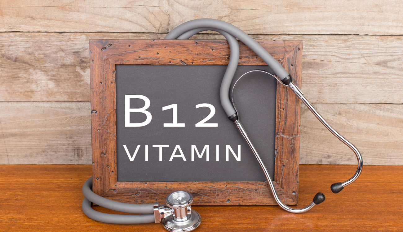 Stethoscope and blackboard with text "Vitamin B12" on wooden background