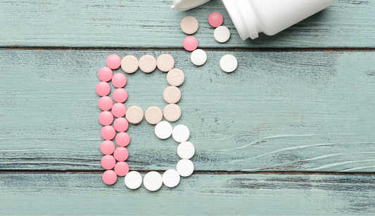 Vitamin B complex pills scattered on a wooden board forming the letter.