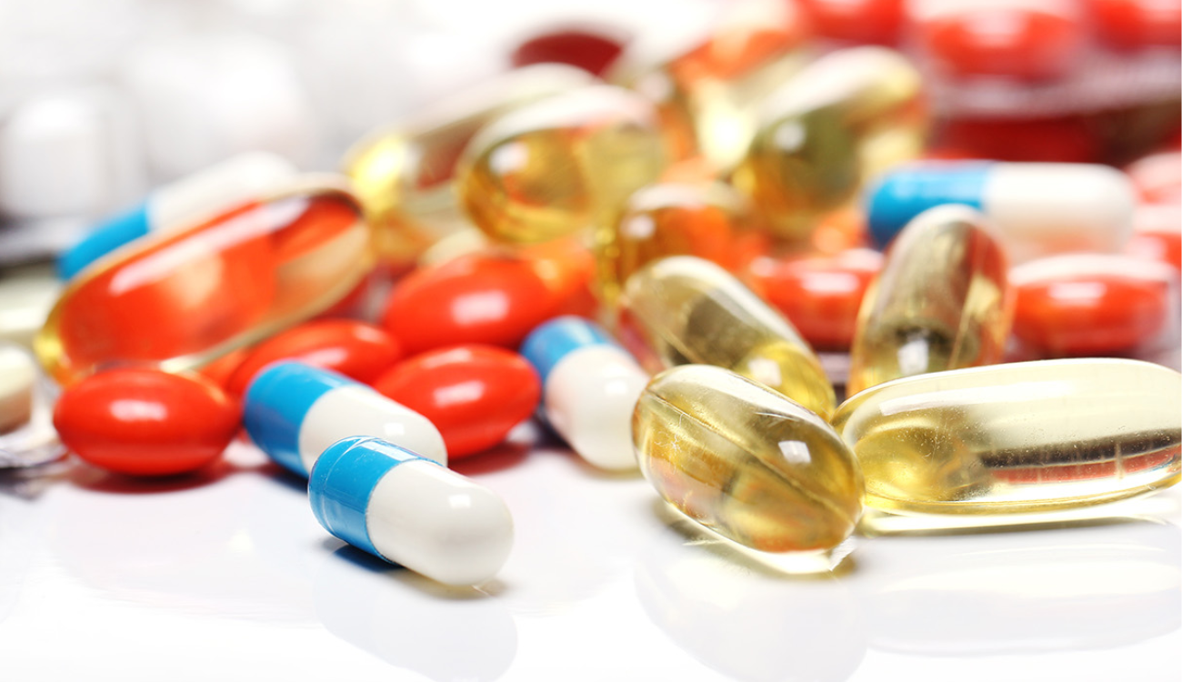 A collection of different types of pills and capsules spread out on a table, indicating a range of supplements.