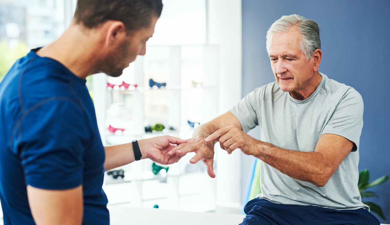 An image of a physical therapist performing a consultation and assessment with an elderly patient who has arthritis.