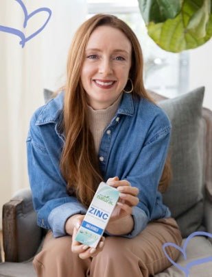 Kelin, founder of Why Not Natural, smiling in a chair holding a product bottle